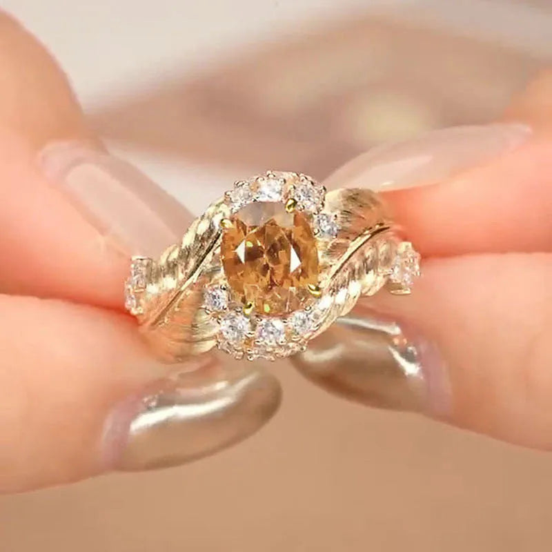 Gold-coloured women's feather ring with embossed design and yellow zircon stones on copper band