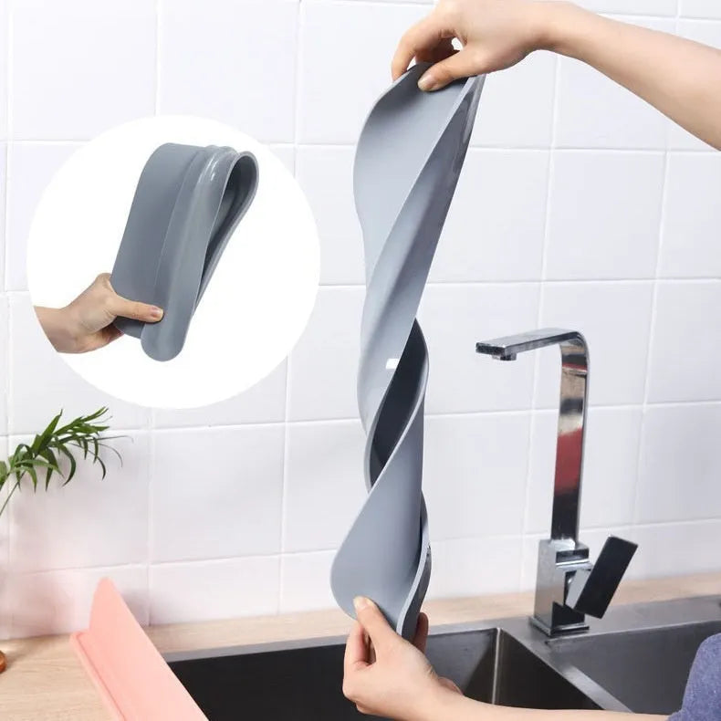 Grey silicone kitchen sink splash guard standing upright on a counter edge.